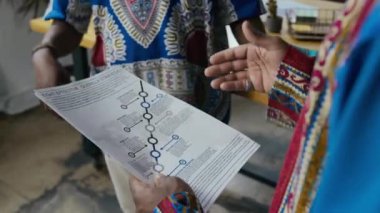 Afrika Dashikis 'teki tanınmayan siyahi adamların, ofiste çalışırken kağıt çizelgeleri ve grafikleri tartışırken ve dağıtırken yakın plan çekimleri.