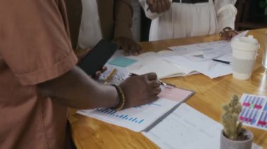 Modern ofis çalışma alanındaki toplantı sırasında iş stratejilerini tartışan şık günlük kıyafetli üç meslektaşın çekimleri.