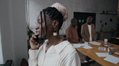 Modern ofiste önemli bir iş görüşmesi yaparken şık giyinmiş Afro-Amerikalı kadın pencereden dışarı bakıyor.