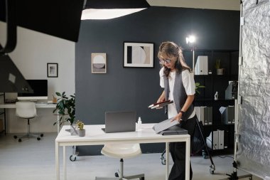 Woman dressed in smart clothes putting notebooks on table before video making clipart