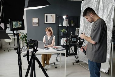 Yapımcı stüdyonun arka planında dizüstü bilgisayarda çalışırken erkek kameraman ayarlama aygıtı