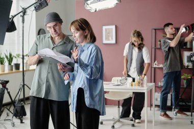 Kafkas yönetmen ve aktris birlikte senaryo okurken, yapım tasarımcısı ve operatör de sahne donanımlarını ve arka plandaki ışığı kontrol ediyor.