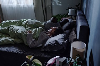 Tanınmayan karı ve kocanın rahat bir yatakta rahat uyuduğu yüksek açılı bir fotoğraf.