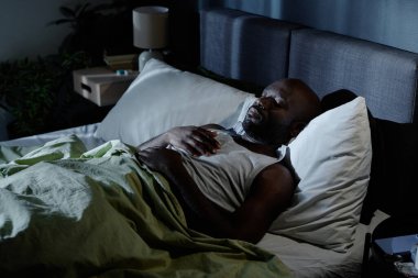 Afrika kökenli Amerikalı bir adamın gece yatakta yattığı yüksek açılı bir fotoğraf.