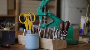 Hiçbir insan makas ve aletlerle konteynırdan vurulmaz, tenteli ahşap alet tutacağı, küçük makas ve iyi organize edilmiş deri atölyesinde ahşap masa üzerinde elle işletilen büyük metal pres.