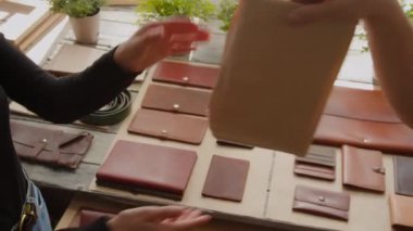 Kadının siparişi kahverengi paketli, deri eşyalar ve atölyede saksı bitkileriyle birlikte geldi.