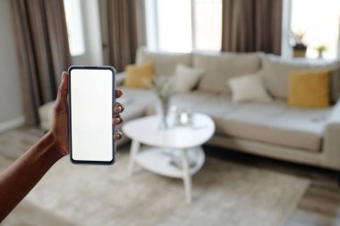 Yüksek açılı, tanınmayan bir kadının oturma odasında akıllı telefonu tutuşu.