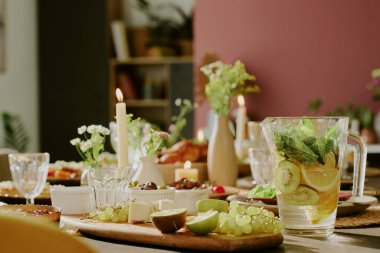 Tahta kesme tahtasında taze meyveler ve kivi ve nane aromalı ev yapımı limonata kavanozu.