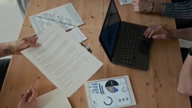 Tanımlanamayan kişilerin grafikler ve grafiklerle belgelerini değiş tokuş ederken, iş görüşmeleri sırasında masada otururken en iyi görüntüsü.