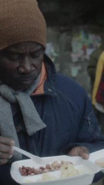 Afro-Amerikalı son sınıf evsiz bir adamın şehir sokaklarında açlıkla mücadele eden hayır kurumları tarafından kendisine bedava yemek yemesine dikey bir bakış açısı.