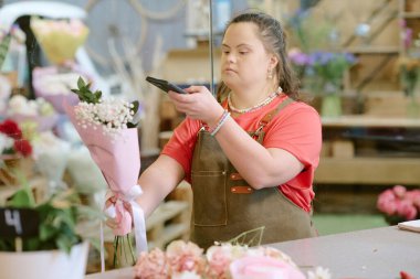 Kafkas 'lı genç çiçekçinin Gypsphila' lı küçük bir buketi tutarken sosyal medyada yayınlamak için yüksek açılı fotoğrafını çektiği orta ölçekli bir fotoğraf.