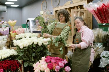 İki çiçekçi birlikte çalışırken çiçekçide gülleri kontrol ediyor.