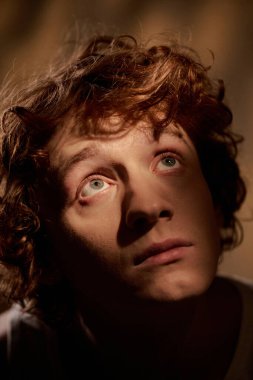 Işıl ışıl yanan bir odada, kızıl saçlı bir adamın orta boy görüntüsü.