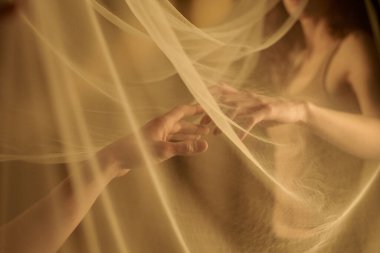 Birbirlerine ulaşmaya çalışan tanınmayan kadın ve erkek elleri.