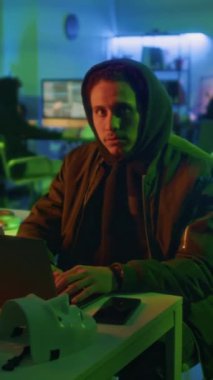 Gece vardiyasında kameraya poz veren kötü niyetli genç erkek oyuncunun portresi dikey zoom.