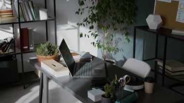 Bilgisayarı, notları, kulaklıkları, saksısı, kırtasiyesi ve kahve fincanı gri masanın üzerinde olan programcıların iş yeri insanların görüşü yok.