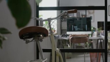 Modern ofisteki cam duvarın önünde deri koltuğu ve gidonu olan klasik şehir bisikletine kimse bakmaz.