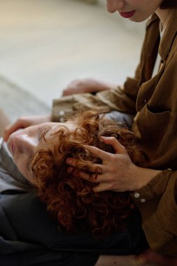 Sevdiği kocasının dizlerinin üzerine çöküp masaj yapan tanınmayan bir kadının dikey çekimi.