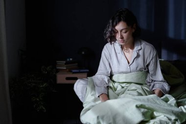 Kafkasyalı bir kadının uyurgezerlikten acı çekerken, yatakta otururken ve ayağa kalkmaya hazırlanırken orta derecede yakın çekim.