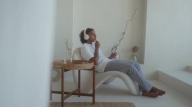 Beyaz tişört ve eşofman giyen, otel banyosunda otururken pamuk ped kullanan Z jenerasyonundaki adam.