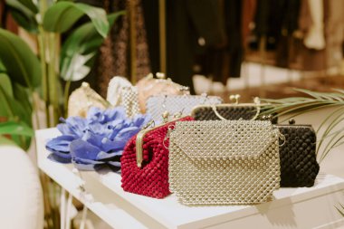 Modaya uygun butiklerde, beyaz masadaki boncuklardan yapılmış çok renkli çantaların orta derecede kapatılması.