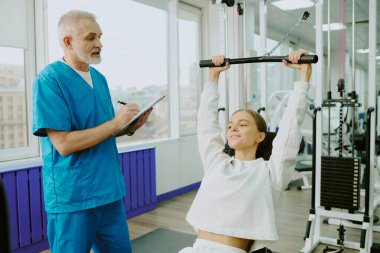 Klinikteki rehabilitasyon sırasında kadın hastaların ağırlık kaldırma egzersizlerinin sonucu olarak doktorların orta derecede kapatılması.