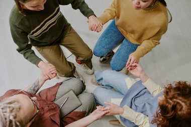 Zeminde el ele tutuşup grup aktivitesi sırasında bağlantı ve birlik oluşturan farklı insanların üst görünümü