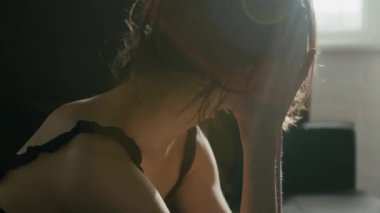 Stresli, siyah kimyasalı olan, başını eğmiş, elleri saçlarının arasından koşan ve evde endişeli hisseden beyaz bir kızın yakın çekimi.