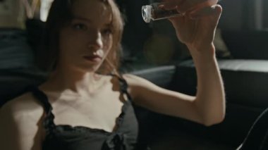 Sinirli beyaz kız, şeffaf şişeden açık ele hapları yavaşça döküyor oturma odasında yere döküyor.