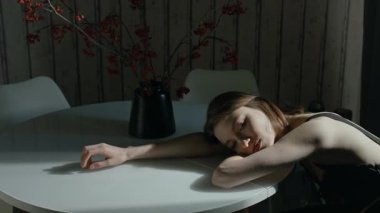 Siyah vazonun yanındaki beyaz yuvarlak masada oturan hayal kırıklığına uğramış kızın başında kırmızı böğürtlenler olan dalları mutfakta duruyordu.