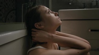 Depresyondaki Z jenerasyonundaki kızın ellerle yüzünü örterken ve banyoda küvete yaslanırken alnını dizlerinin üstüne koyarken yakın plan çekimi.
