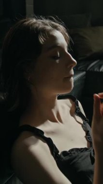 Harap olmuş bir kızın reçeteli ilaç alıp suyla içmesi ve oturma odasındaki deri koltukta dinlenmesi.