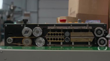 Metal silindirli, dişli, kayışlı ve makaralı mekanik aygıtla yeşil yüzeye yerleştirilmiş kahve kızartıcı tesiste konveyör sisteminin yakın çekim görüntüsü.