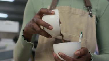 Önlüklü, Afro-Amerikan kadın kızartma makinesinin kahve çekirdeklerini kızartma tesisinde bir kaseden diğerine dökerkenki yavaş çekim görüntüleri.