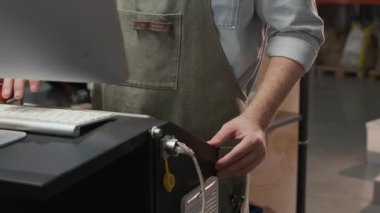 Gözlüklü ve önlüklü sakallı erkek işçinin kahve kızartma fabrikasındaki terminalde klavyede daktilo kullanırken çekilmiş bir fotoğrafı.