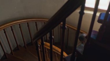 Siyah cüppeli, katedraldeki ahşap merdivenleri tırmanan, İncil kitabı olan Afro-Amerikan Katolik bir rahip.