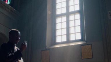 Afrika kökenli Amerikalı rahibin Katolik kilisesine girerken kutsal İncil 'i tutarken kendini kutsaması, sonra da çerçeveyi terk etmesi.