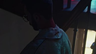 Altın beyazı cüppeli genç rahip ahşap merdivenlerden iniyor ibadet sonrası loş ışıkta katedrali terk ediyor.