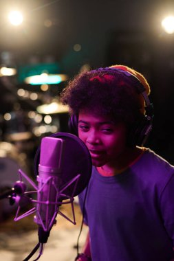 Dikey yüksek açı, kulaklıklı çocuğu stüdyoda mikrofona şarkı söylerken çekti.