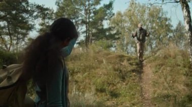 Sırt çantalı genç bir kızın davetkar bir jestle babasını aramasının odak noktası. Sonra yürüyüş direklerini kullanarak hızla tepeden aşağı doğru yürüdü.