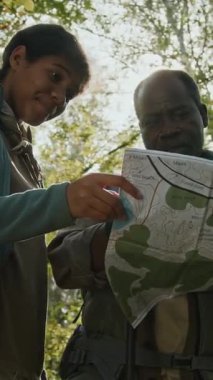 Afrika kökenli Amerikalı baba ve kızının ormanda yürüyüş yaparken haritada rota seçmeleri