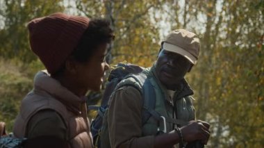 Baba ve oğlunun yürüyüş kıyafetleri içinde birbirleriyle konuşurken ve sonbaharın başlarında aile kaçamağı sırasında etraflarına bakarken çekilen fotoğrafları.