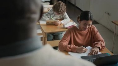 Modern okul sınıfındaki öğrencisinin sorularını cevaplayan Afrikalı Amerikalı erkek öğretmenin omuz üstünden.