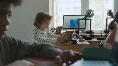 Modern okul sınıfında 3D modellik dersi sırasında dizüstü bilgisayar ve dijital tabletler kullanan ilkokul öğrencileri