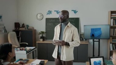 Modern ilkokulda 3D modellik dersi sırasında aktif öğrencilerin ve Afro-Amerikan erkek öğretmenlerin el kamerası görüntülerini büyüt.