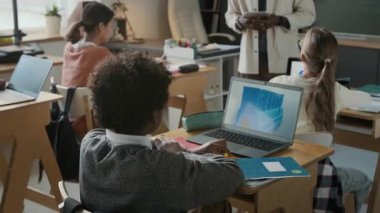 Tanımlanamayan Afro-Amerikan erkek öğretmen öğrencileriyle etkileşimde, el kaldırıyor, modern ilkokul sınıfında.