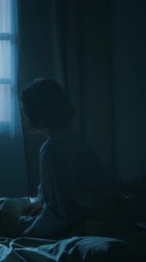 Dikey çekimde genç bir kadın uyanıyor ve yataktan kalkıyor, geceleri kolları önünde uykusunda yürüyor.