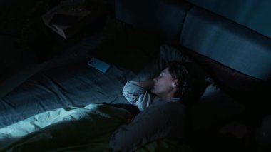 Genç bir kadının, geceleri rahat bir yatak odasında uyurken fırlattığı yüksek açılı bir fotoğraf.