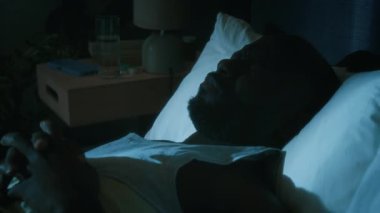 Afrika kökenli Amerikalı bir adam kötü bir rüyadan uyanıyor ve su içiyor. Geceleri çevre dostu yatak odasında yatağının başucundaki bardaktan cam alıyor.