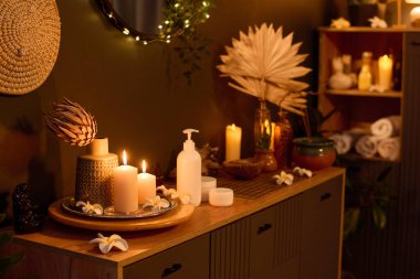 Yanmış aroma mumları, kurutulmuş çiçekler ve kremalı masaj yağıyla kaplı orta boy ahşap kaplama.